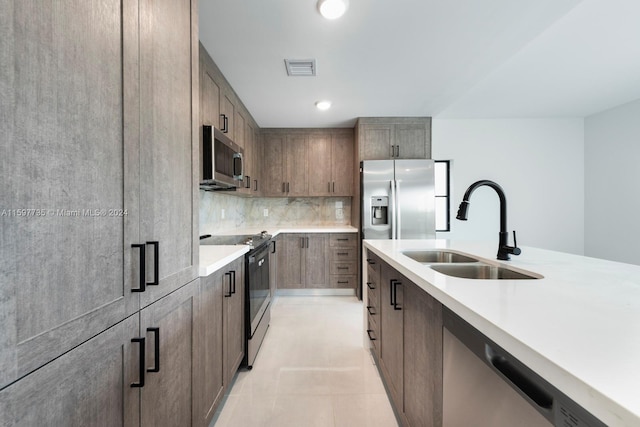 kitchen with light tile patterned flooring, stainless steel appliances, sink, and decorative backsplash