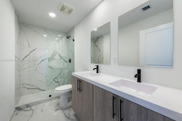 bathroom featuring a tile shower, vanity, and toilet