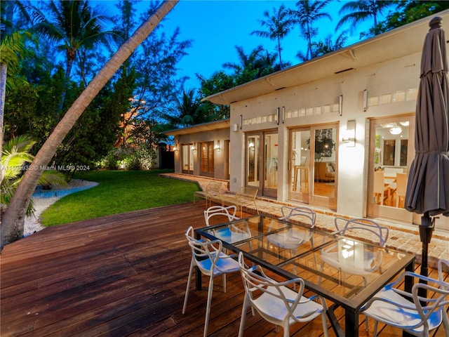 wooden deck with outdoor dining space and a yard