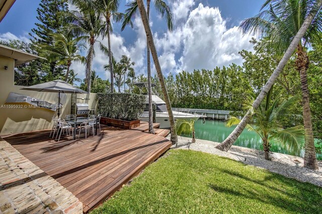 wooden terrace with a boat dock and a lawn