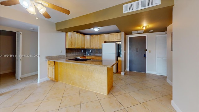 kitchen with kitchen peninsula, decorative backsplash, white refrigerator, and light tile patterned floors