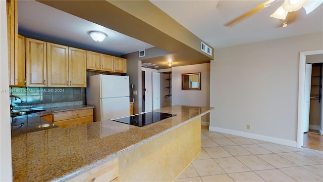 kitchen featuring black electric stovetop, light brown cabinets, white fridge, and sink