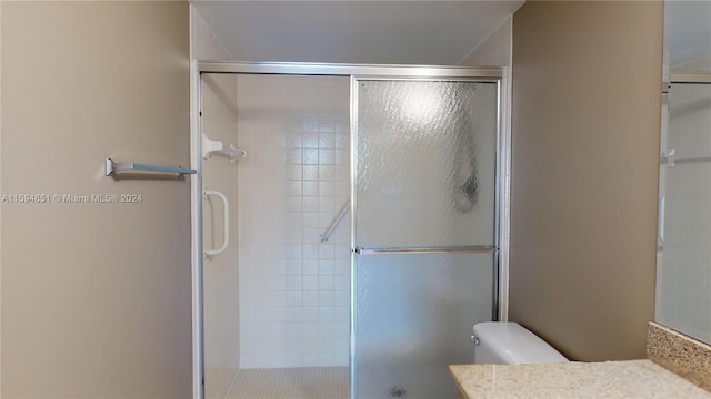 bathroom featuring vanity, toilet, and a shower with shower door