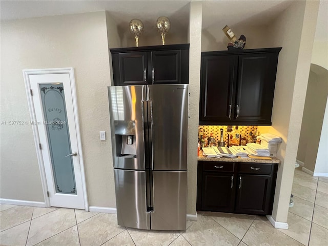 kitchen featuring stainless steel fridge, backsplash, dark brown cabinetry, and light tile patterned flooring