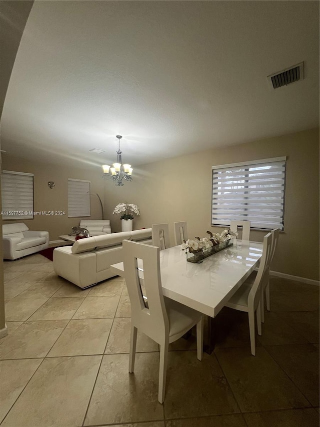 dining space with light tile patterned floors and an inviting chandelier