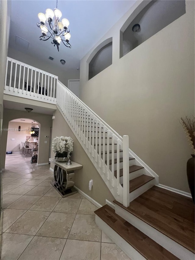 stairway with tile patterned flooring and a notable chandelier