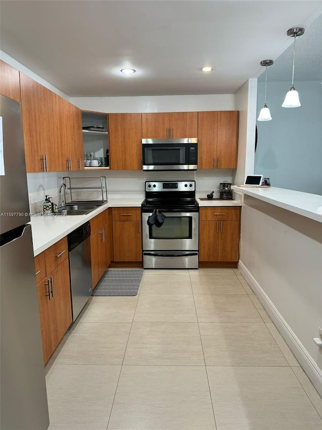 kitchen with light tile patterned flooring, appliances with stainless steel finishes, hanging light fixtures, and sink