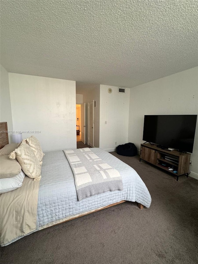 bedroom featuring dark carpet and a textured ceiling