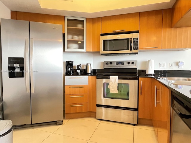 kitchen featuring stainless steel appliances, sink, and light tile floors