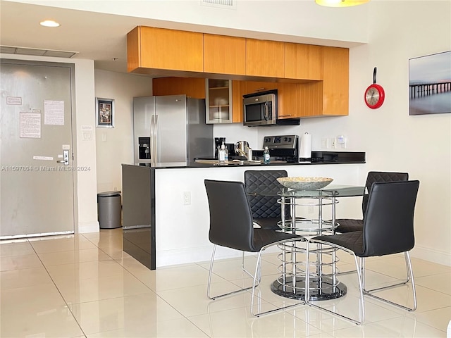 kitchen featuring appliances with stainless steel finishes, light tile floors, and kitchen peninsula