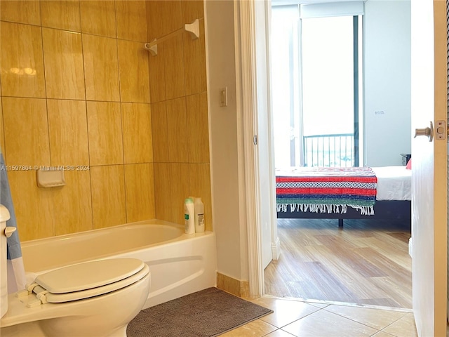 bathroom featuring bathing tub / shower combination, a healthy amount of sunlight, toilet, and wood-type flooring