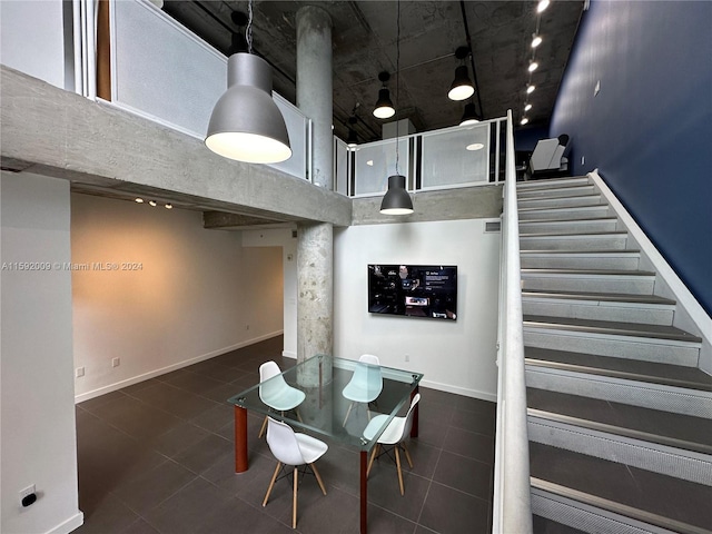 dining space featuring dark tile patterned flooring and a high ceiling