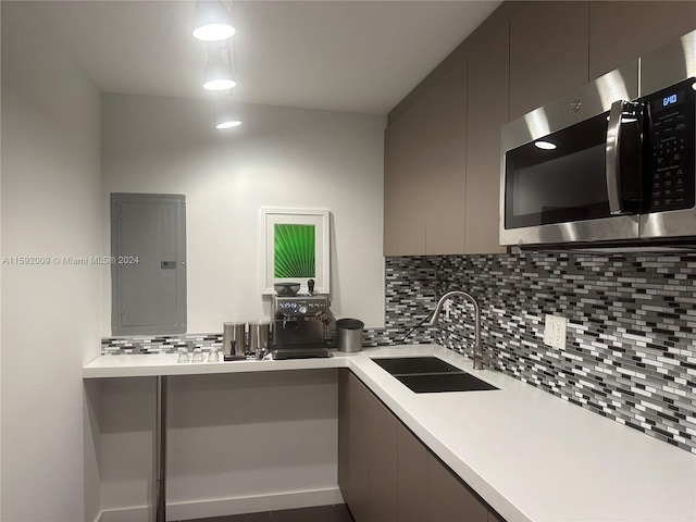 kitchen with backsplash, electric panel, sink, and gray cabinetry