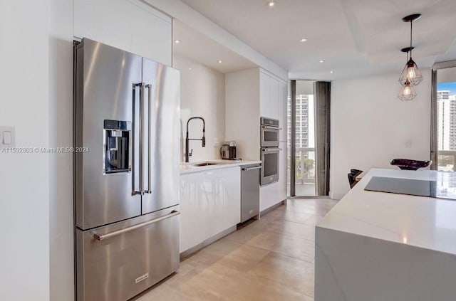 kitchen with a healthy amount of sunlight, light stone counters, white cabinetry, and appliances with stainless steel finishes