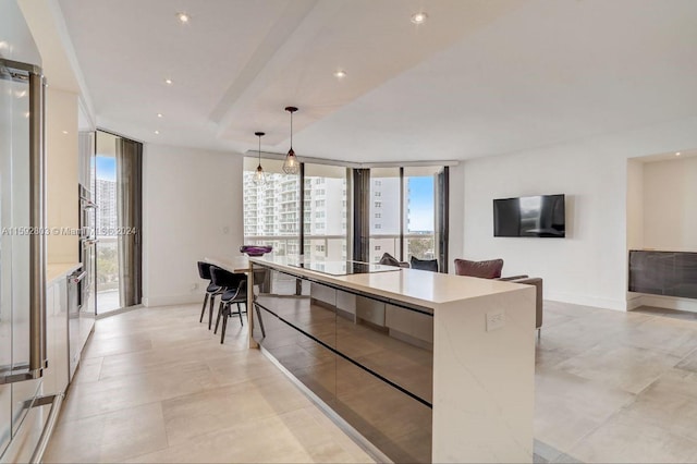 kitchen with black electric stovetop, plenty of natural light, a center island, and decorative light fixtures