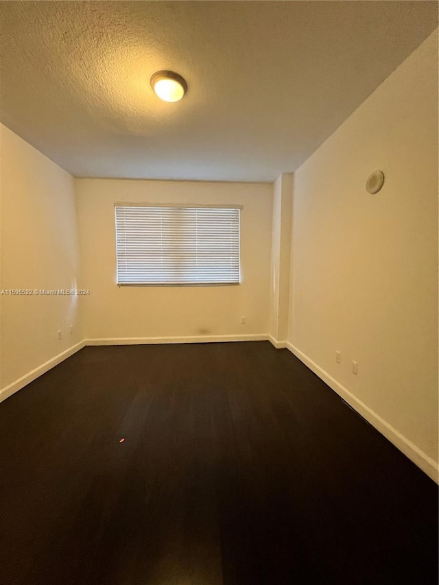 spare room featuring wood-type flooring and a textured ceiling