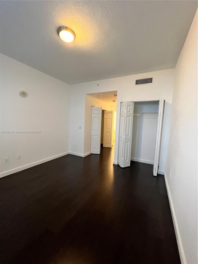 spare room with dark hardwood / wood-style floors and a textured ceiling