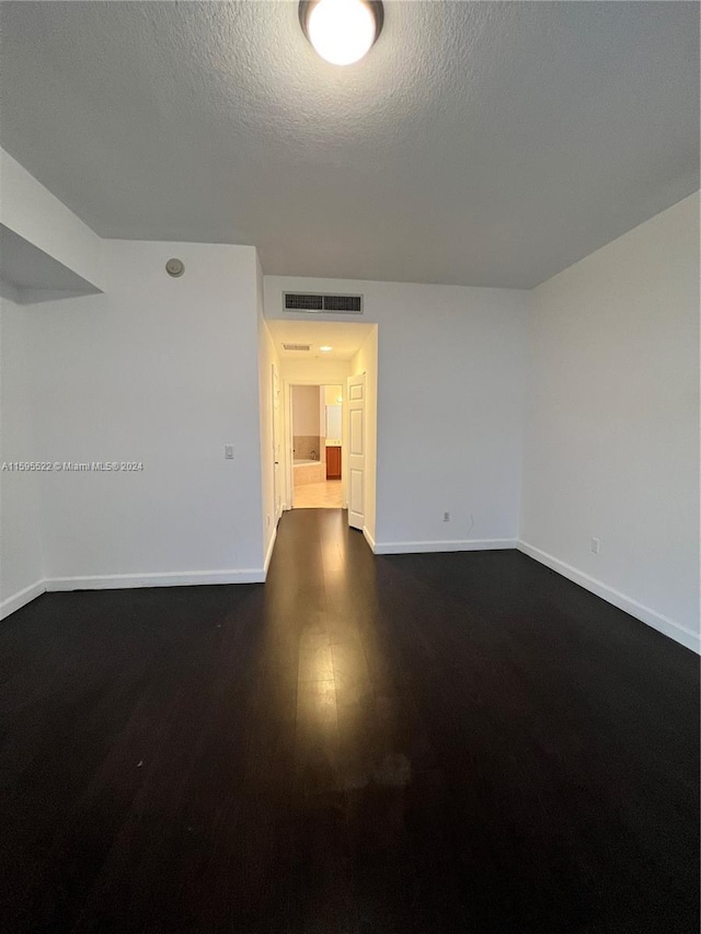 unfurnished room featuring dark hardwood / wood-style floors and a textured ceiling