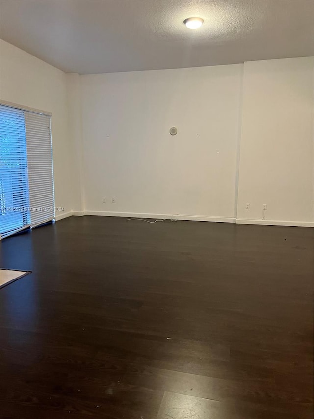 unfurnished room featuring dark hardwood / wood-style floors and a textured ceiling