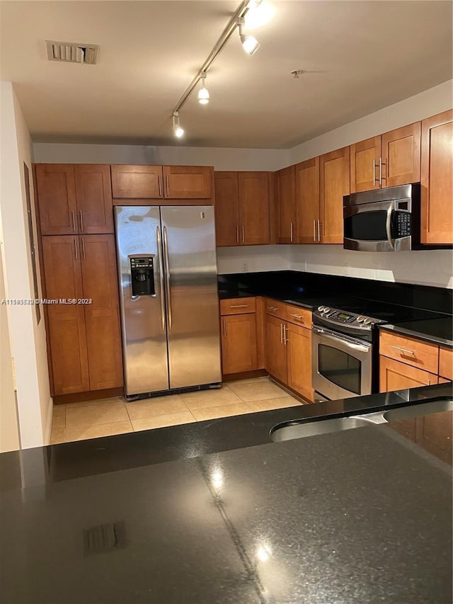 kitchen with light tile patterned floors, stainless steel appliances, and rail lighting