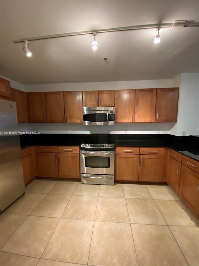 kitchen with light tile patterned floors, appliances with stainless steel finishes, and track lighting