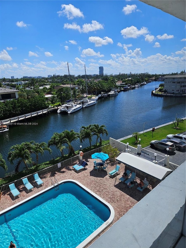 view of swimming pool featuring a water view and a patio