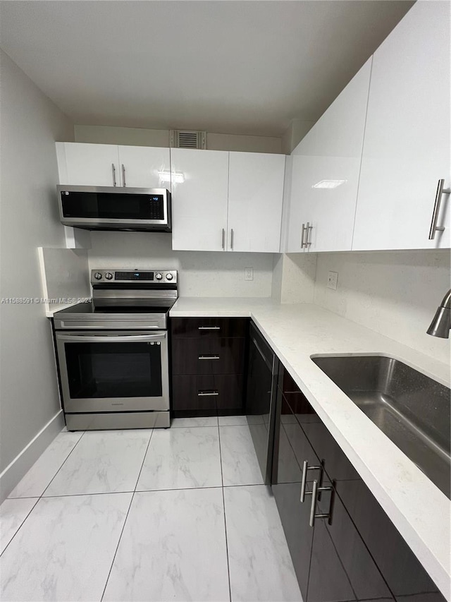 kitchen featuring stainless steel appliances, white cabinetry, sink, and dark brown cabinetry