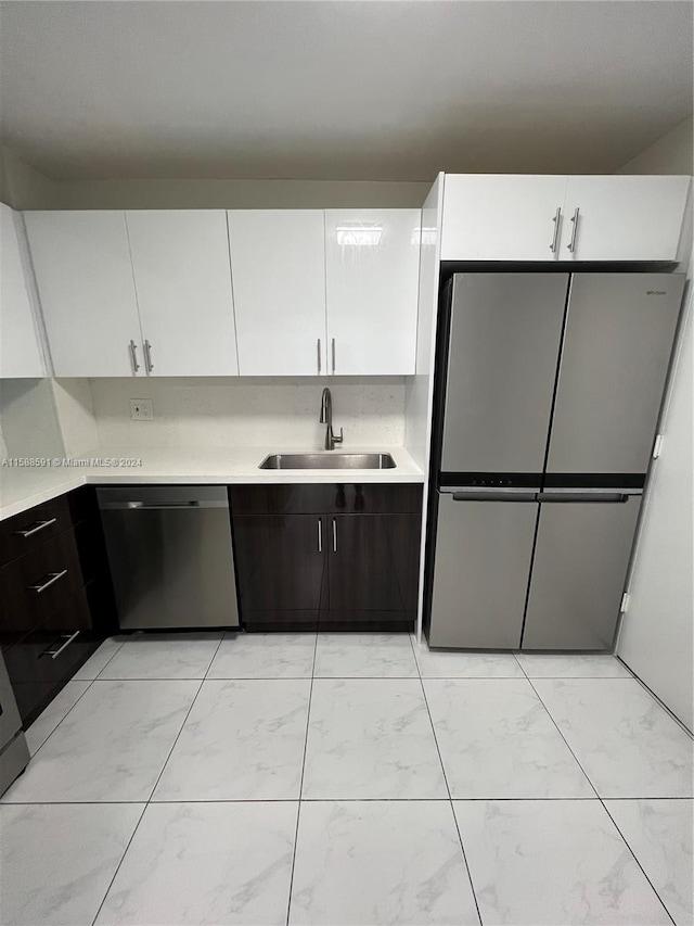 kitchen with white cabinets, sink, dark brown cabinetry, and appliances with stainless steel finishes