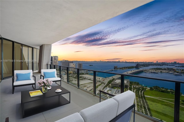 balcony at dusk with outdoor lounge area and a water view