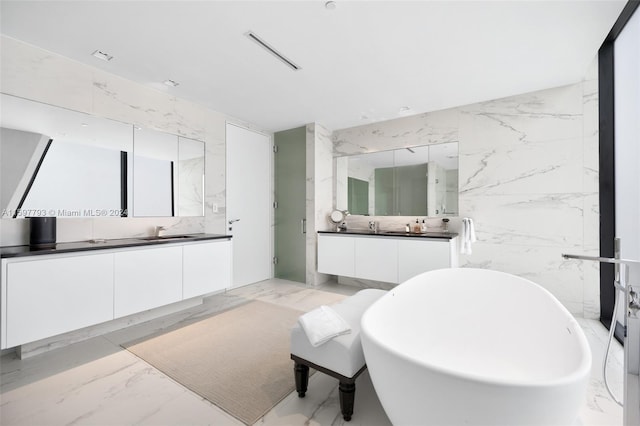 bathroom featuring a washtub, tile patterned floors, vanity, and tile walls