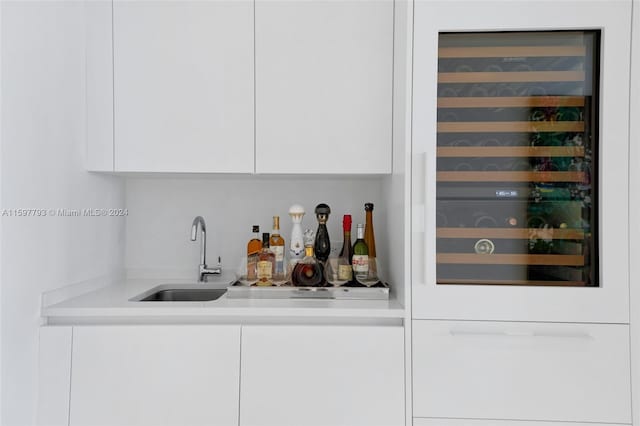 bar with sink, beverage cooler, and white cabinets