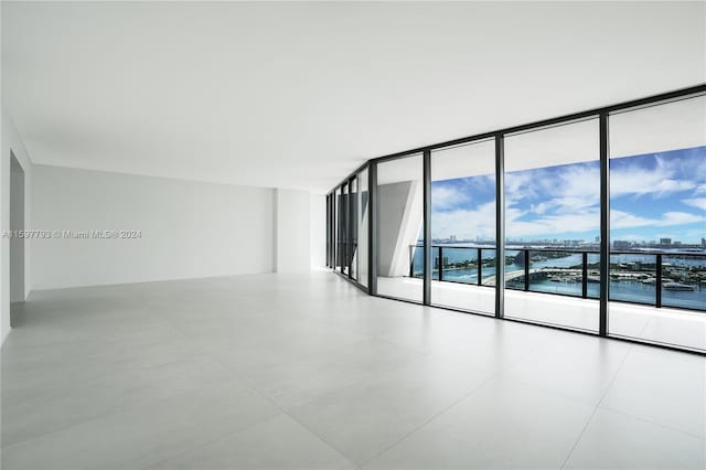 spare room with tile patterned flooring, expansive windows, and a water view