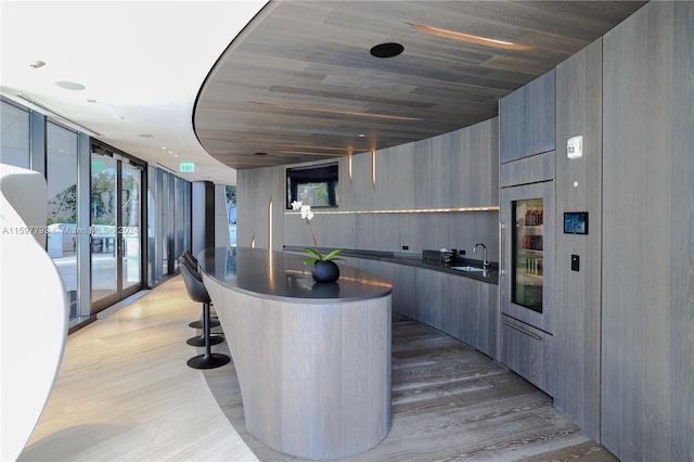 interior space featuring sink, wooden ceiling, a wall of windows, and wood-type flooring