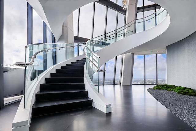 stairway with a wall of windows, a high ceiling, and a water view