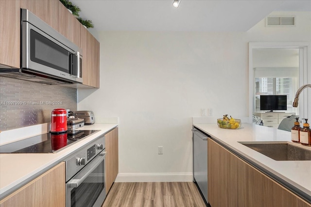 kitchen featuring light hardwood / wood-style floors, sink, backsplash, and appliances with stainless steel finishes