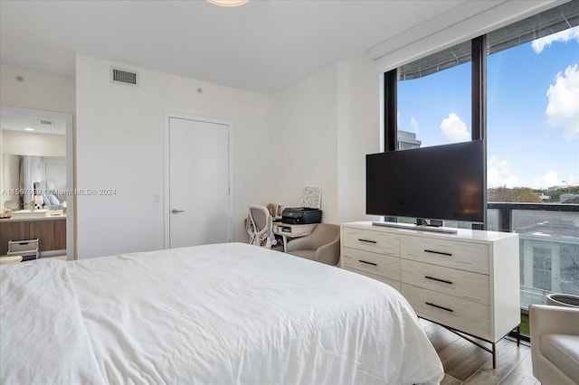 bedroom with light hardwood / wood-style floors and ensuite bath