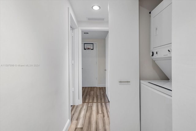 washroom with light wood-type flooring and stacked washer / dryer