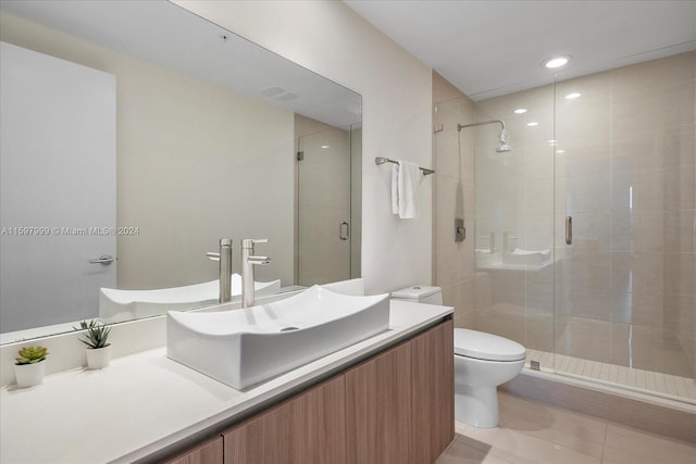 bathroom with tile patterned floors, vanity, a shower with shower door, and toilet