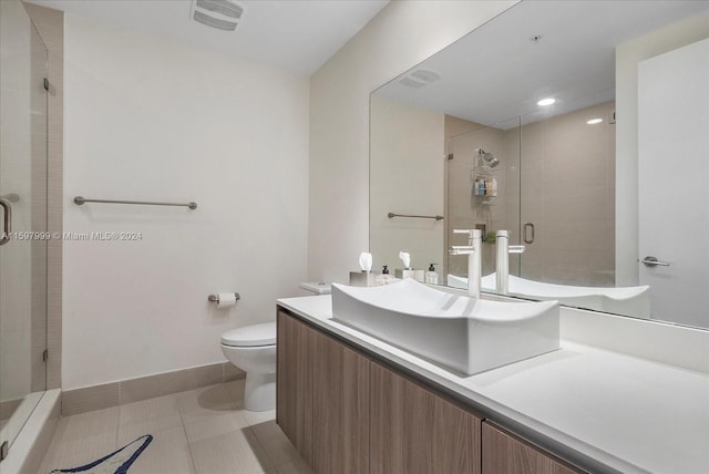 bathroom with tile patterned flooring, vanity, toilet, and a shower with door