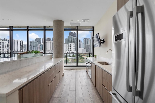 kitchen with stainless steel fridge, a wealth of natural light, a wall of windows, and sink