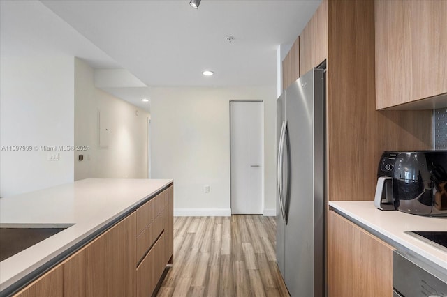 kitchen featuring oven, stainless steel fridge, sink, and light hardwood / wood-style flooring