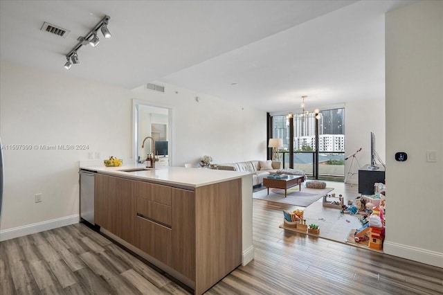 kitchen featuring kitchen peninsula, sink, stainless steel dishwasher, and light hardwood / wood-style floors