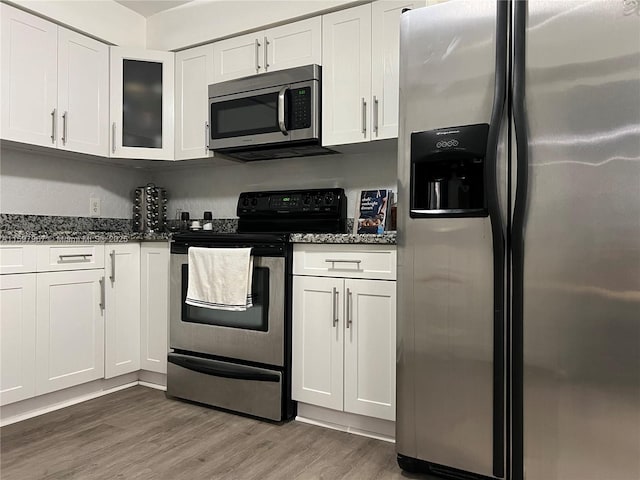 kitchen with white cabinetry, appliances with stainless steel finishes, and dark stone countertops
