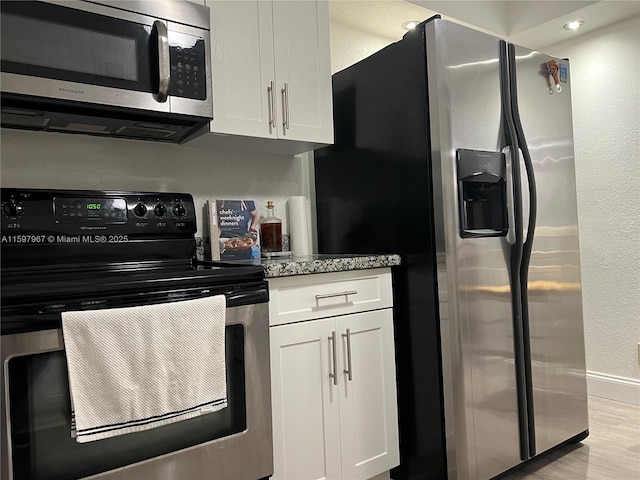 kitchen featuring white cabinetry, light stone counters, light hardwood / wood-style floors, and appliances with stainless steel finishes
