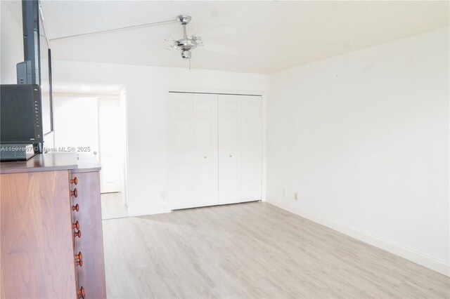 unfurnished bedroom with a textured ceiling, light hardwood / wood-style flooring, a closet, and ceiling fan