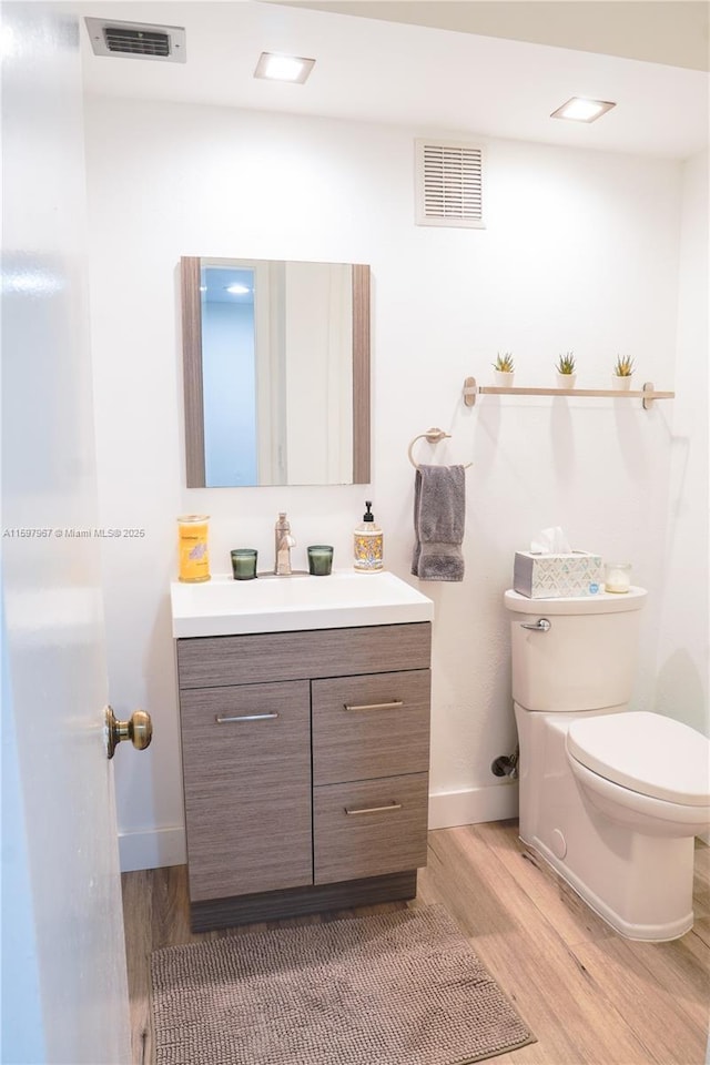 bathroom with wood-type flooring, toilet, and vanity