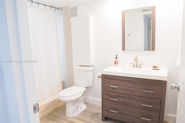 bathroom with hardwood / wood-style flooring, vanity, walk in shower, and toilet