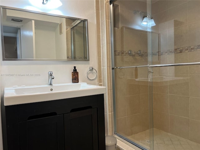 bathroom featuring a shower with door and vanity