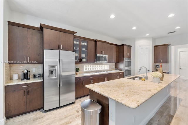 kitchen with sink, stainless steel appliances, an island with sink, light hardwood / wood-style floors, and dark brown cabinets