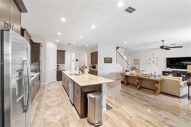 kitchen featuring light stone countertops, stainless steel appliances, sink, a center island with sink, and light hardwood / wood-style floors